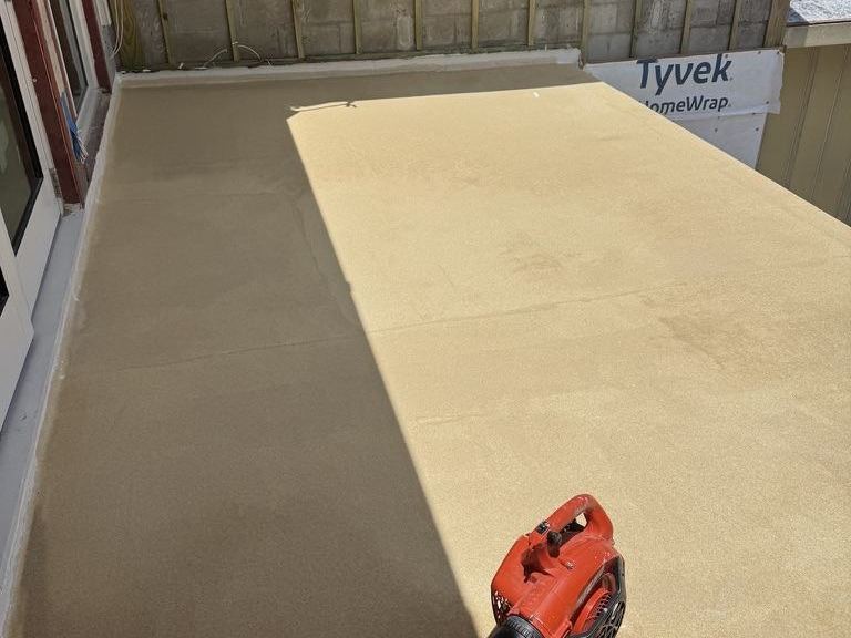 Textured waterproof deck coating blown clean on a balcony enclosed by a CMU wall
